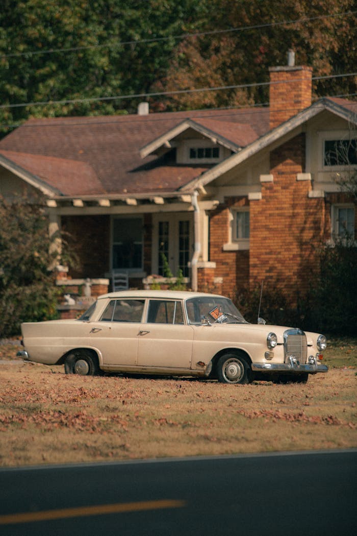 A vintage car parked outside a rustic house, evoking nostalgia in a rural setting.